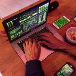 person using macbook pro on brown wooden table